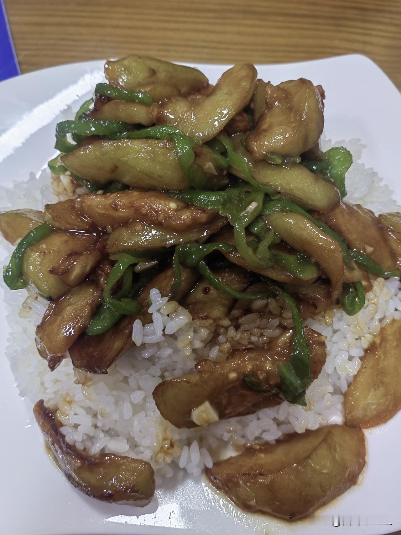 今天中午吃的茄子盖浇饭，软糯入味的茄子裹着浓稠酱汁，青椒的鲜脆在齿间跳跃，每一口