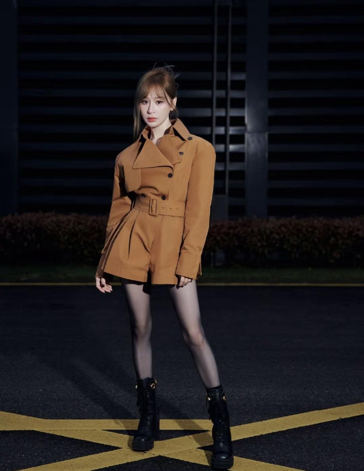 黑丝+短靴的搭配，是舞台造型的加分项：既中和了风衣的中性感，又增添了一丝小性感和