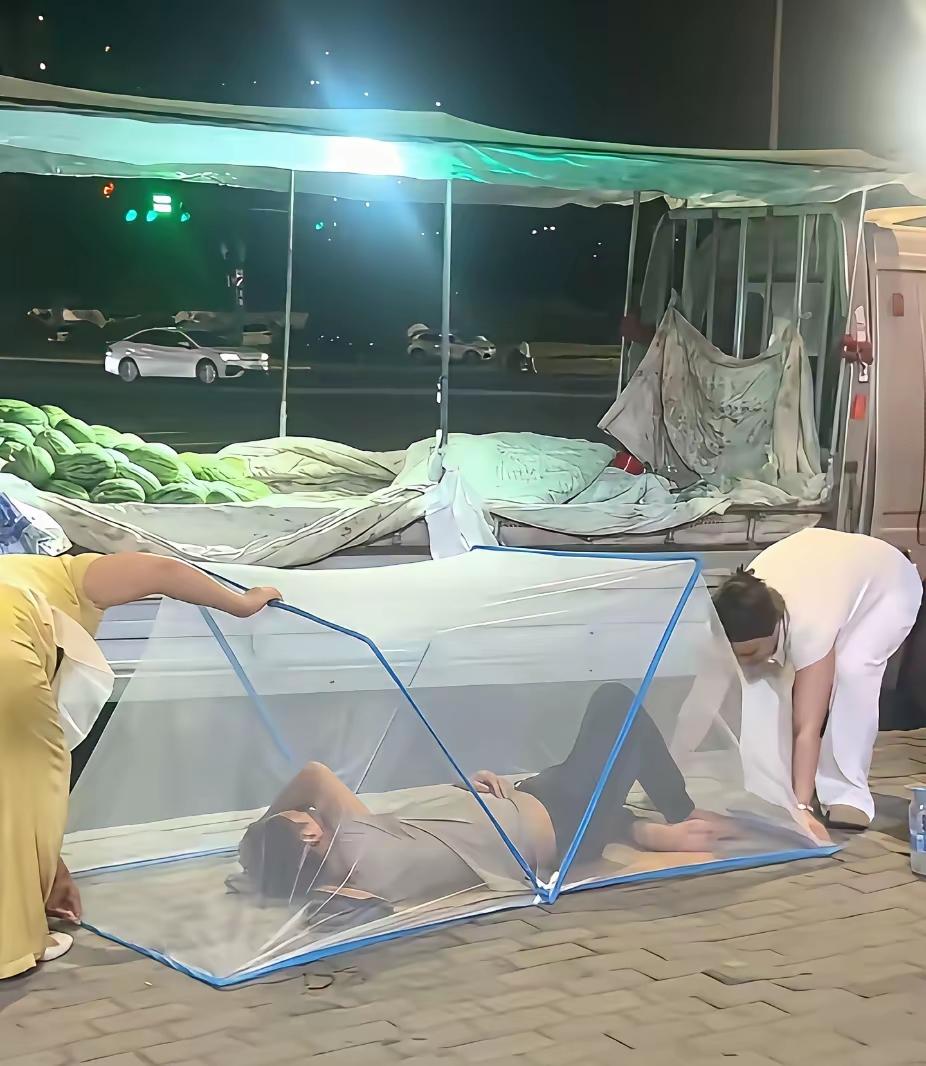 郑州街头夜色已深，卖西瓜的摊主累了一天，在西瓜摊前人行道上和衣而睡盛夏的夜晚