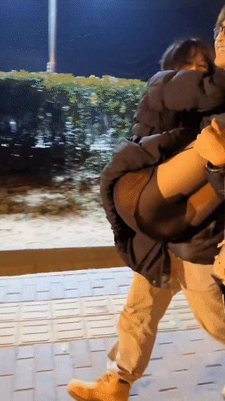 一名男生深夜接在夜场上班的女朋友下班回家。只见他抱着女朋友在街头行走，两个人看