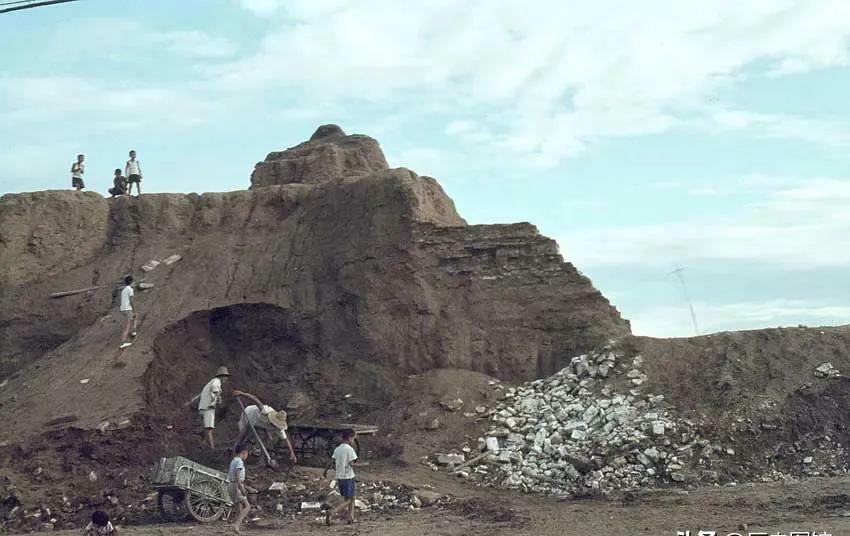 1966年，北京市中心一段城墙下，几名市民正在取土，拉回家垫地。昔日高大雄伟的北