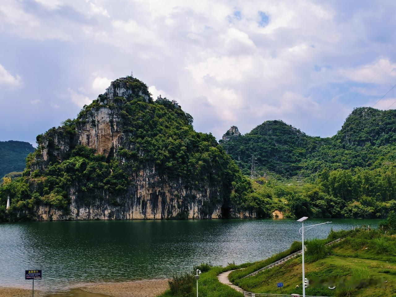 这就是广西独有的喀斯特山水，一座孤峰直接矗立在碧绿湖水边，岩壁裸露又长满茂密绿植