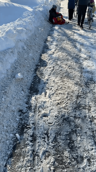 一名中国男子在冰天雪地的俄罗斯街头拍到一位年轻的妈妈抱着孩子坐在雪地里乞讨要钱，