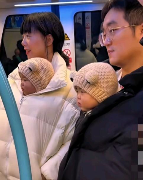 地铁车厢里，一对夫妻胸前各抱着个粉团似的双胞胎宝宝，俩小家伙长得几乎一模一样，被