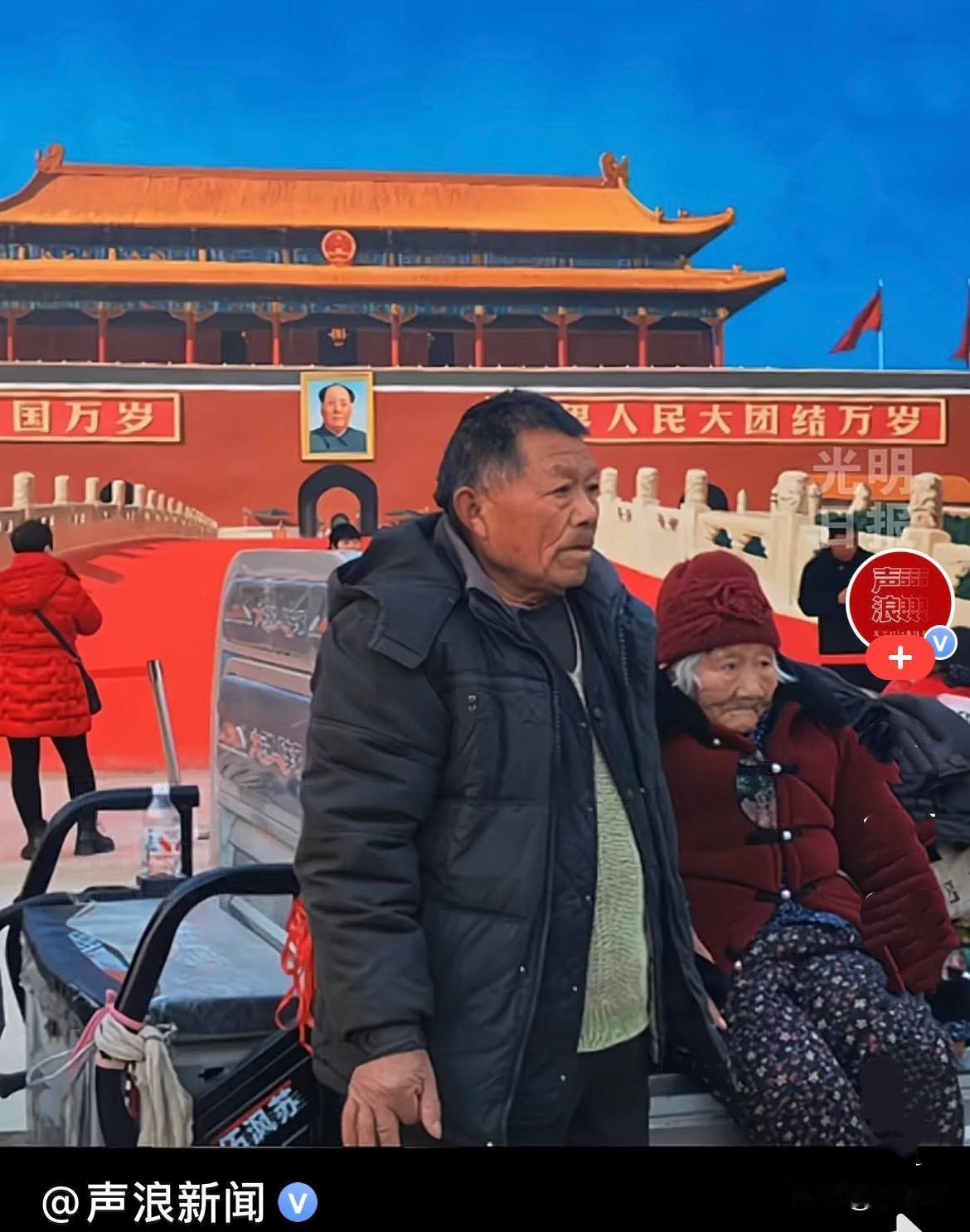 近日，河南吴营村“天安门”墙画前，一位大叔骑着三轮车带着腿脚不便年迈的母亲来了，