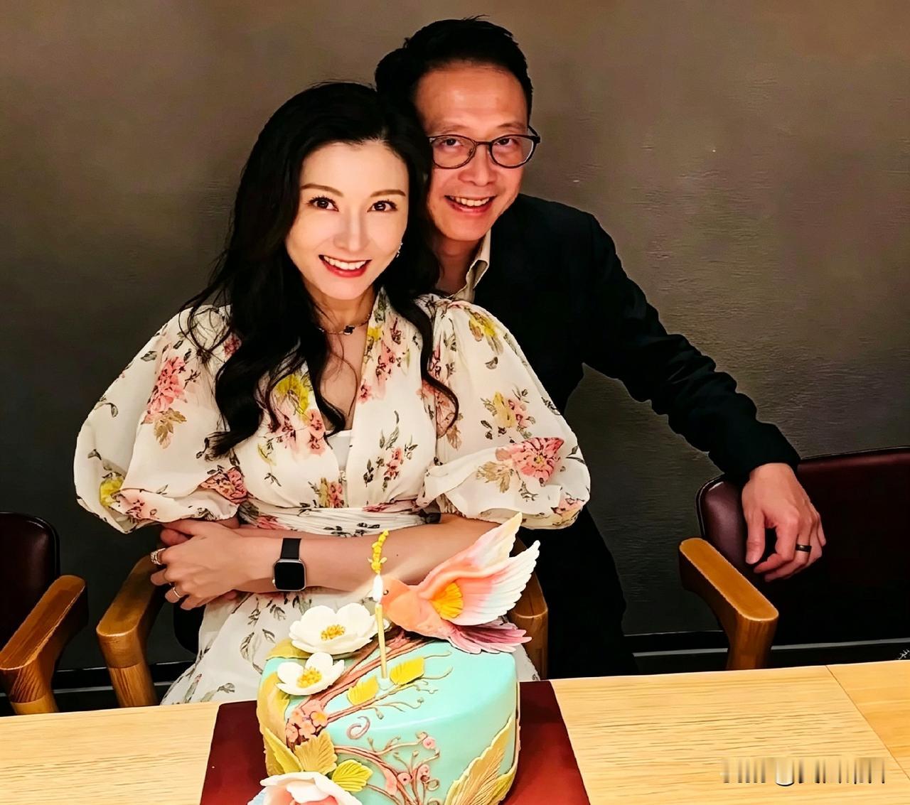 李嘉欣在香港的家里过生日，老公许晋亨从背后搂着她，俩人笑得特别开心。面前摆着一个