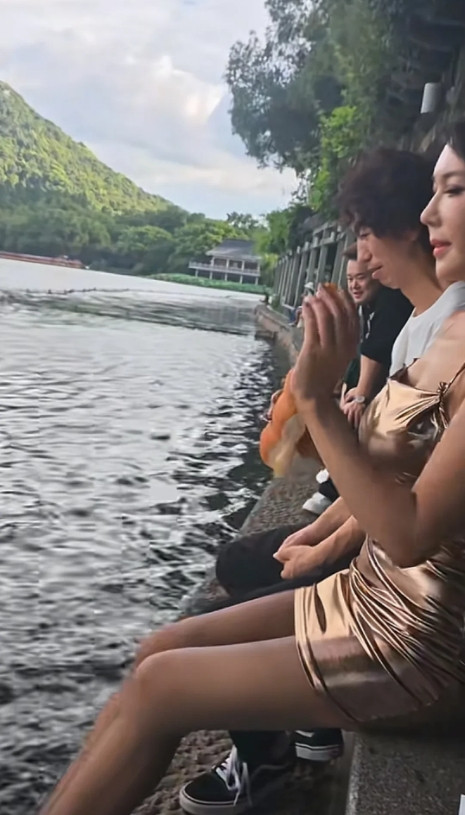 龚玥菲庞麦郎后续，俩人坐在西湖边喂鱼。主要是龚玥菲拿着面包在喂，庞麦郎则坐在旁边