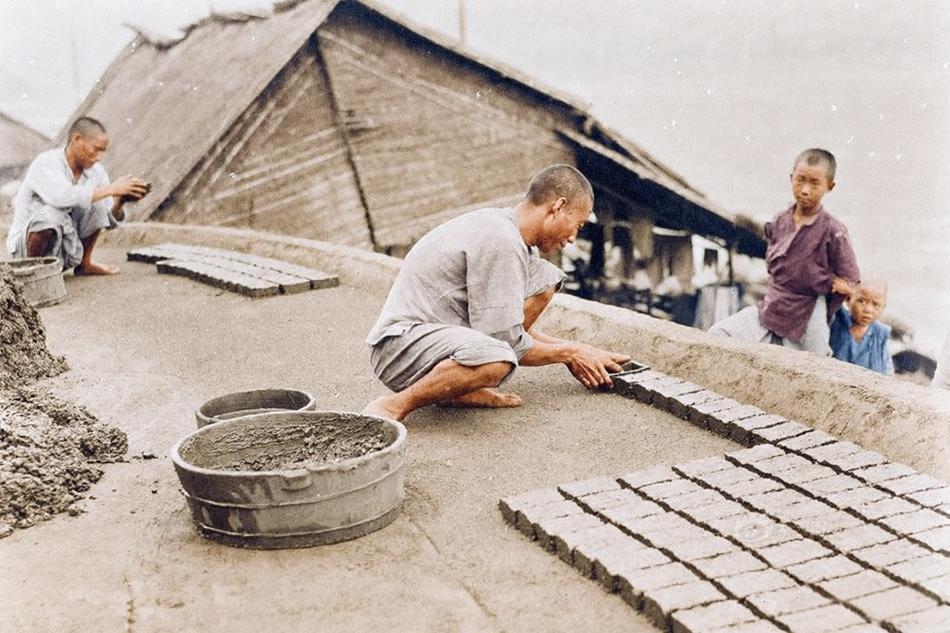 1917年，重庆城区一处高台，几名工人蹲坐在平整的高台地面上专注操作，一人用手将