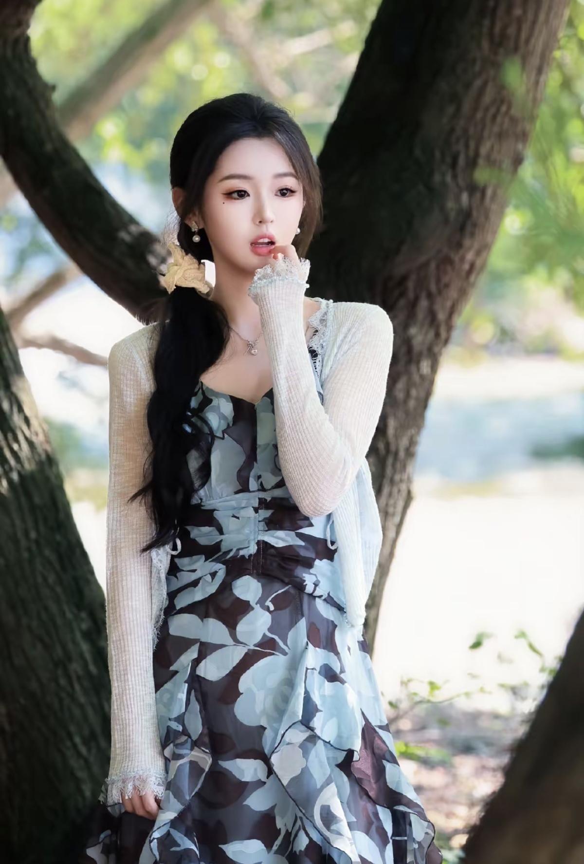 低马尾配上蝴蝶结发饰，置身树荫之下，光影落在裙身，清甜又灵动，像从森林故事里走出