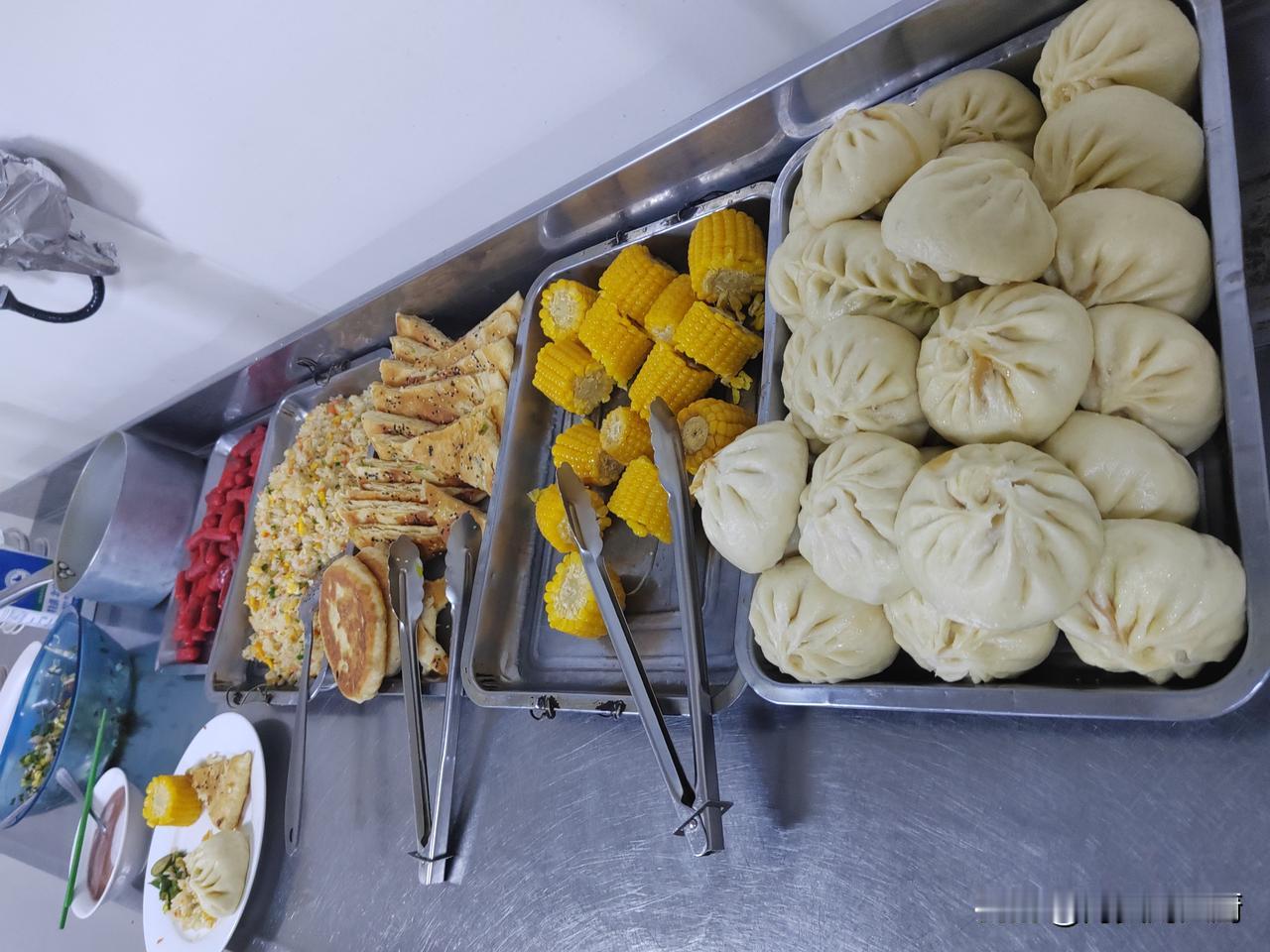 今天的早餐做了蒸包，油饼，蛋炒饭，糯玉米，香肠，鸡蛋，小咸菜，熬的八宝粥，还有牛