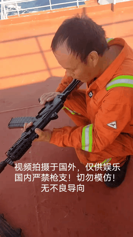 一位在国际远洋货轮上工作的中国大叔正在把玩一把自动步枪？他看起来真是有点爱不释