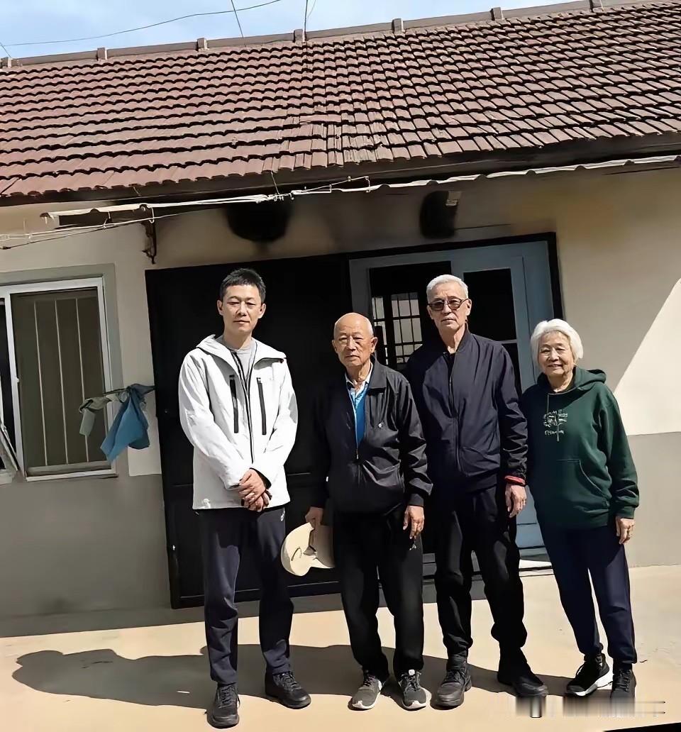 张译一家人的合影挺温馨的，张译穿搭简约，看着比较接地气。一家人在老房子前的温