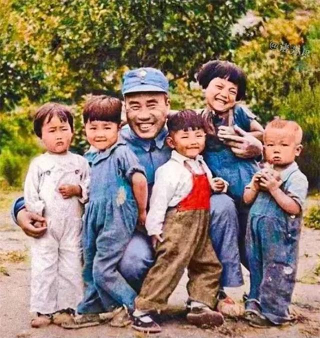 1938年的延安郊外，绿树环绕的空地上留下了这张动人的彩色老照片。朱老总蹲在一群