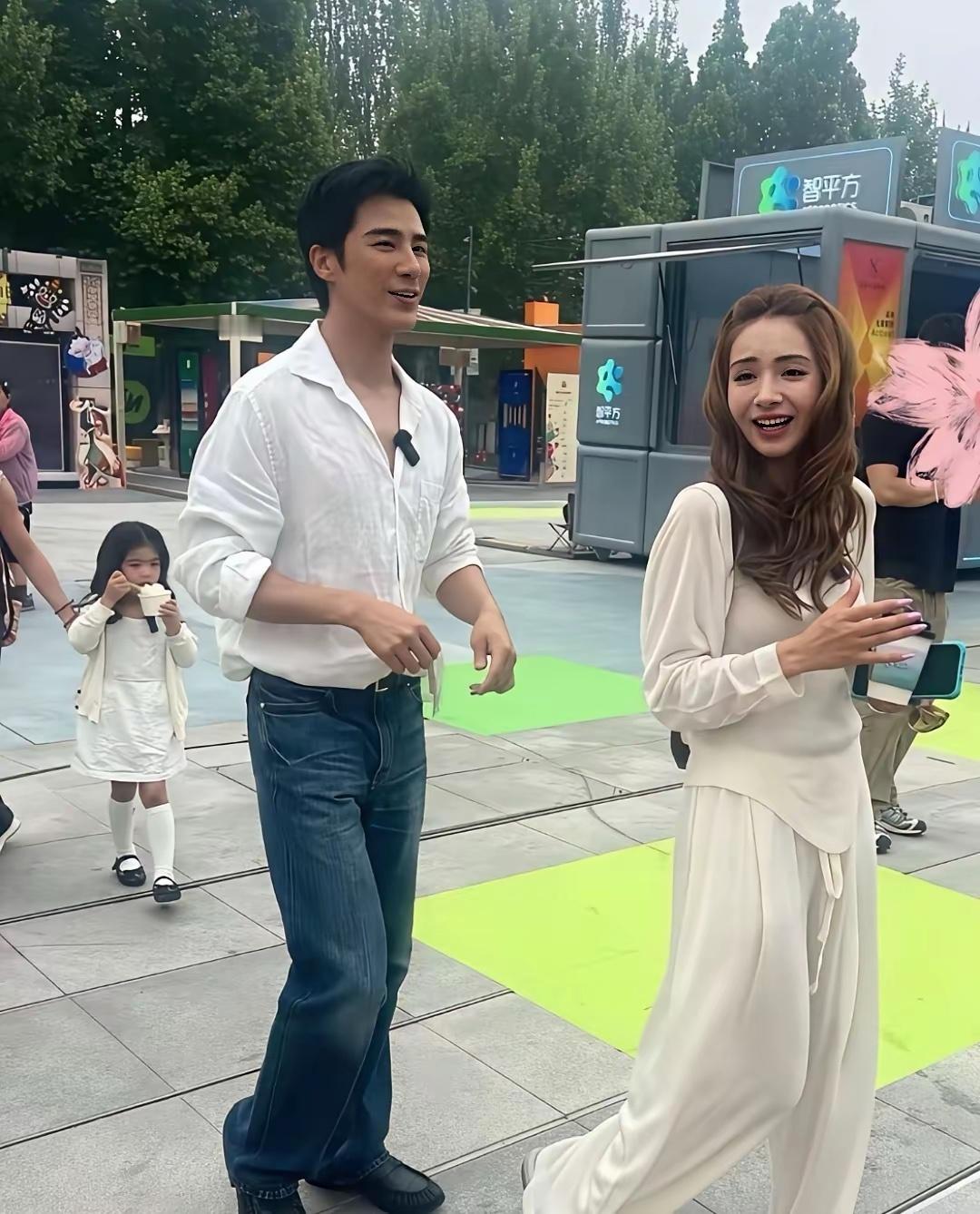 麦迪娜⁠和老公姜潮⁠带着一对子女在北京逛美食街，她和女儿都留着长卷发，颜值非常高