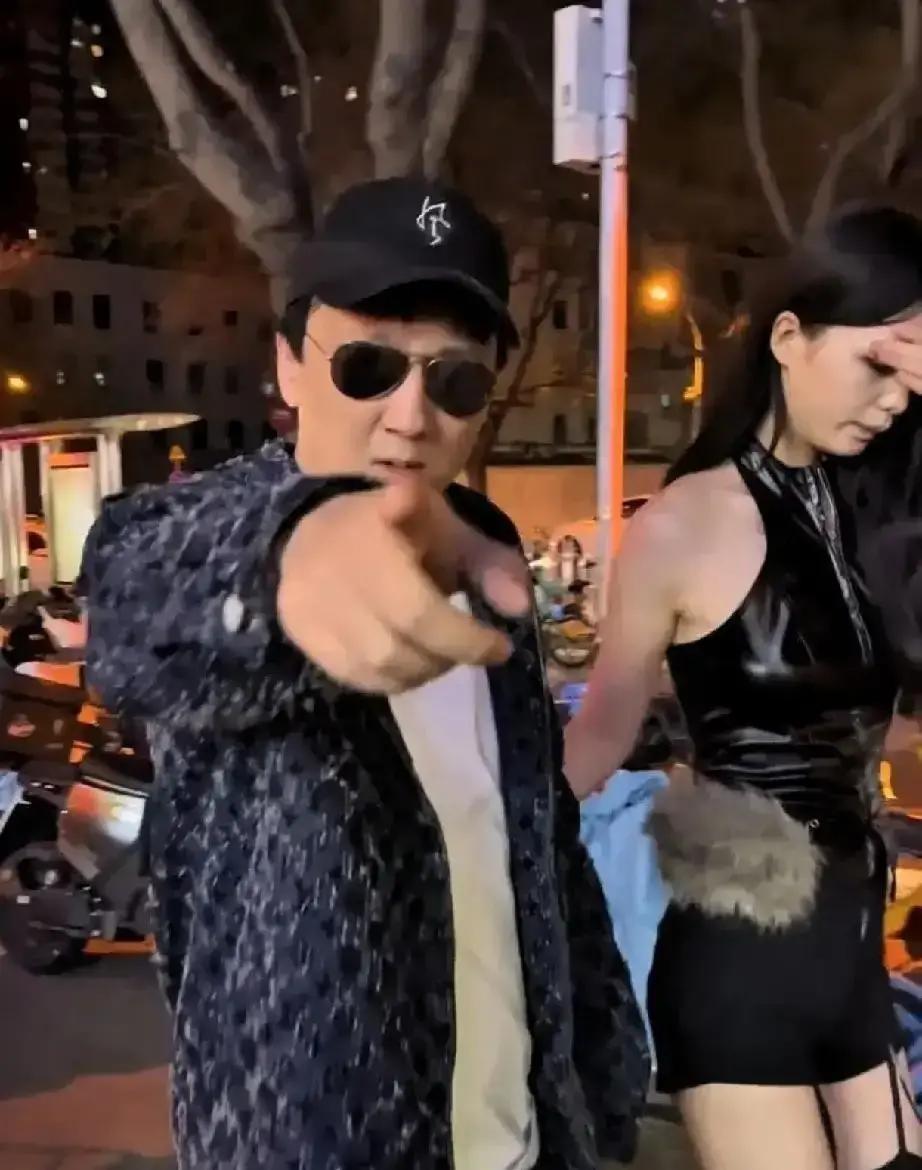 假思聪在新天地街头直播，一身西装墨镜，身边围着助理，拎着大牌购物袋摆拍。路人拿