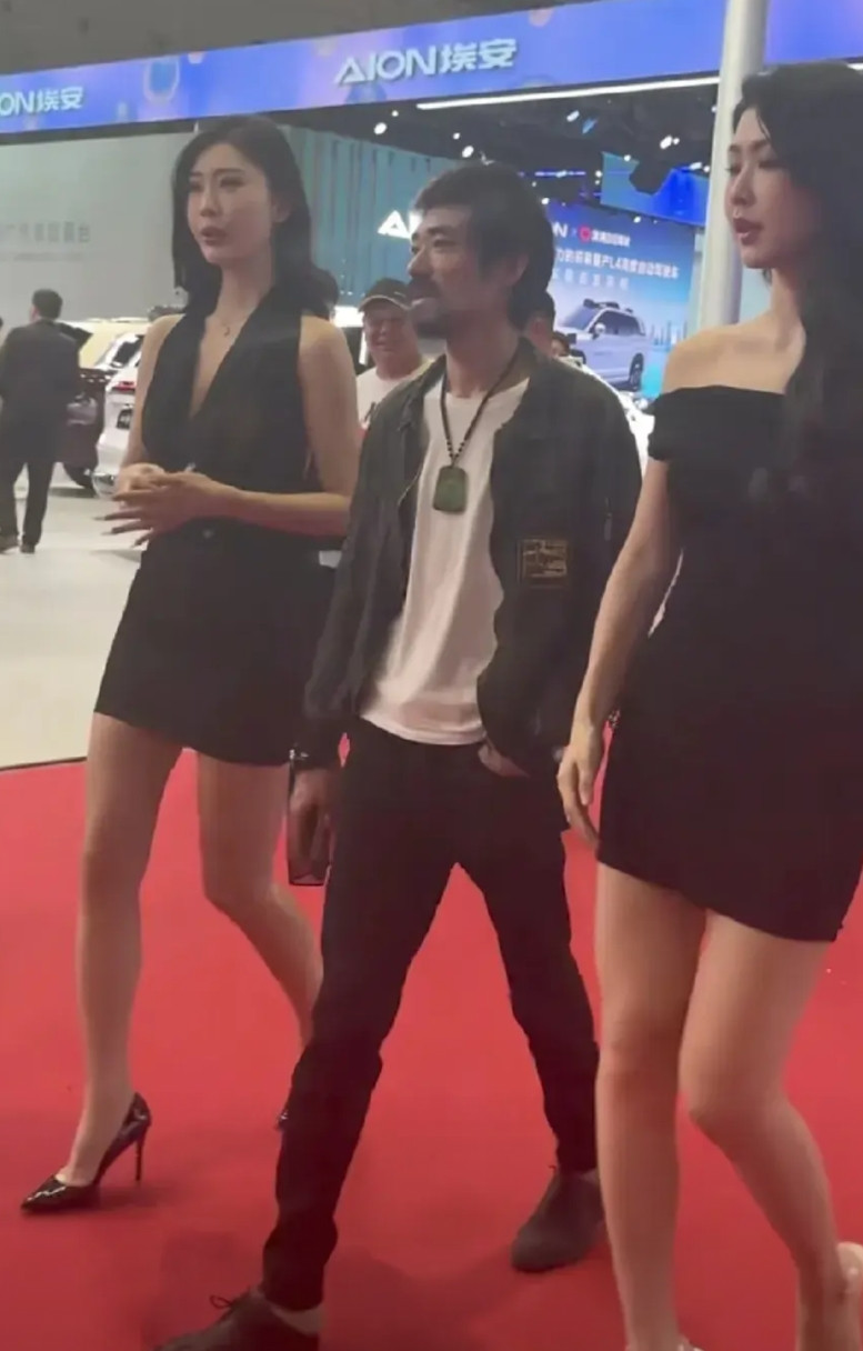 上海车展一位男士，身材瘦弱，一身“脏兮兮“，背后还有一个窟窿，其貌不扬，和模特们