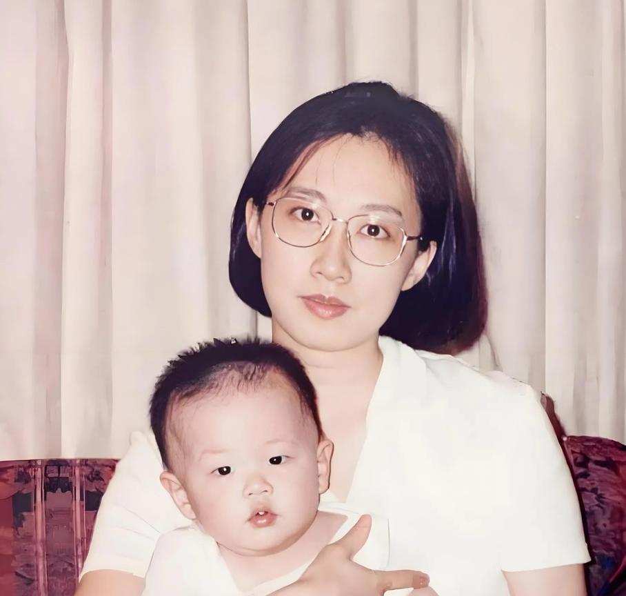 90年代，李敖妻子王小屯抱着周岁的儿子李戡的留影旧照，穿着白上衣，五官秀丽，知性