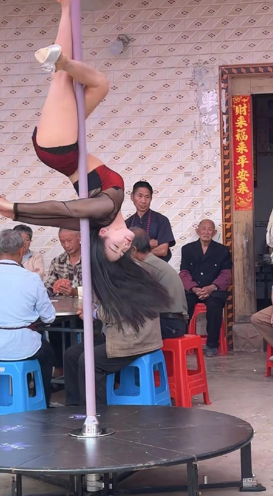 农村老人八十大寿的宴席上，年轻女孩踩着超高跟鞋，在钢管上完成着高难度的翻转、劈叉