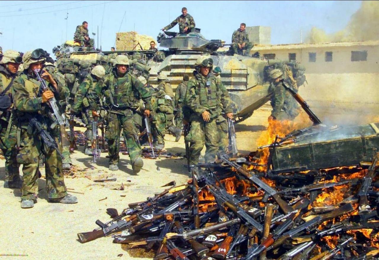 一张2003年拍摄的照片，画面中驻伊拉克美军士兵站在装甲车辆旁，前景处是一大堆正