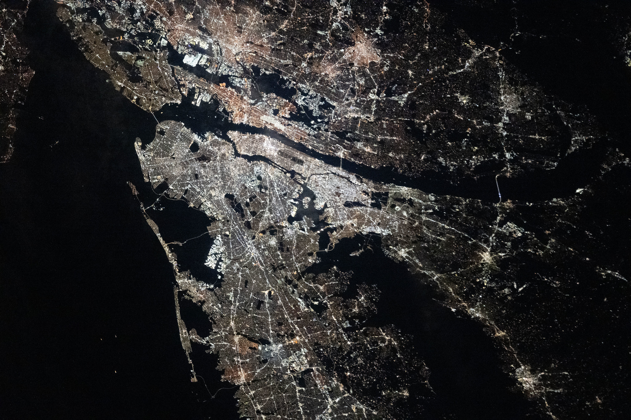 从太空轨道俯瞰，纽约市与新泽西呈现出令人惊叹的昼夜反差：白天，密集而规整的城市街