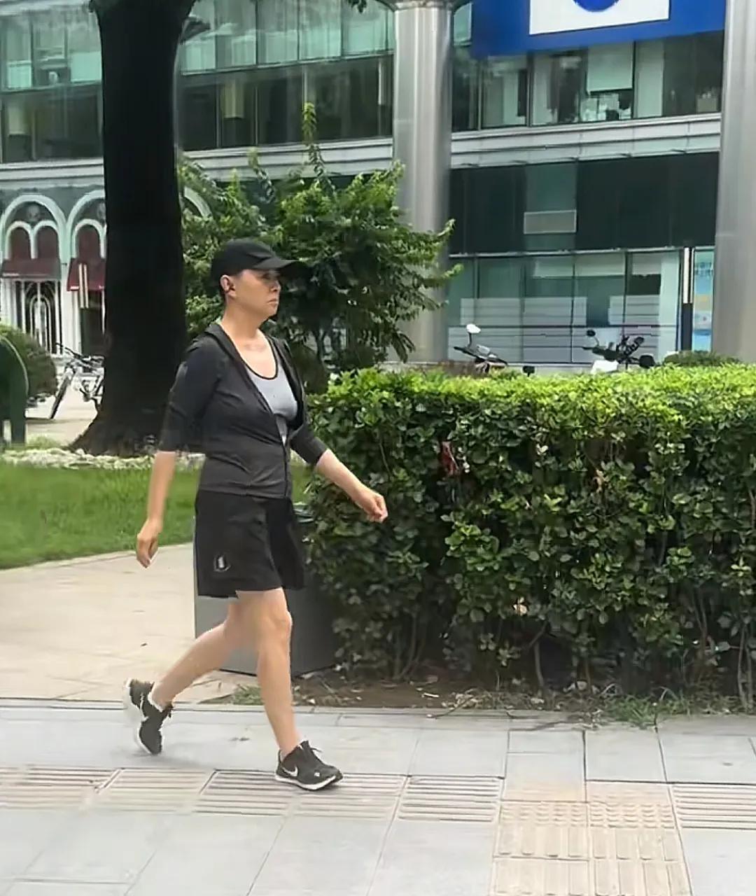 65岁宋丹丹在北京街头散步，穿着一身运动服，头戴鸭舌帽，英姿飒爽，表情严肃，气势
