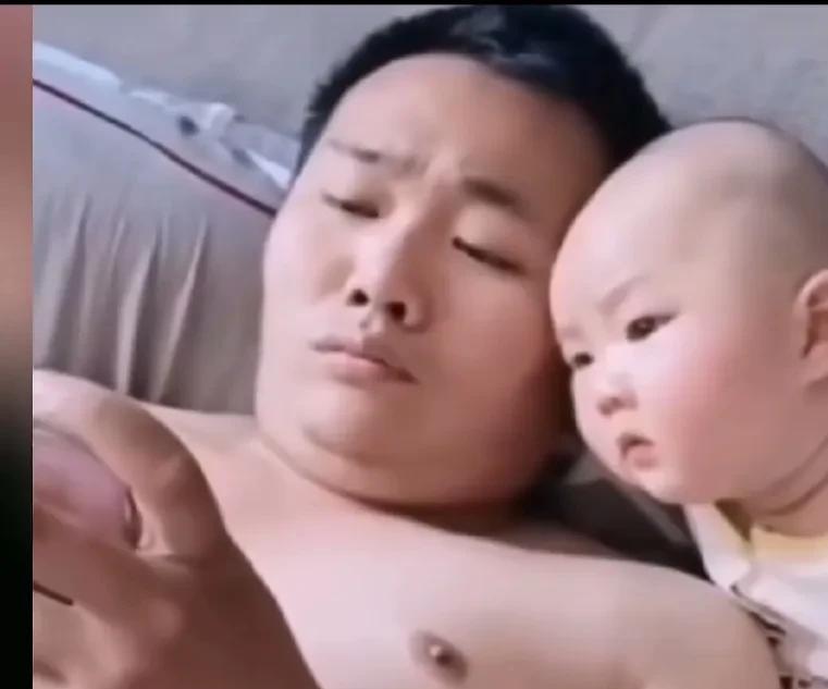 爸爸躺在床头看手机，宝宝伸着头也跟着瞅，爷俩看的眼睛都不眨。妈妈很好奇，究竟看的