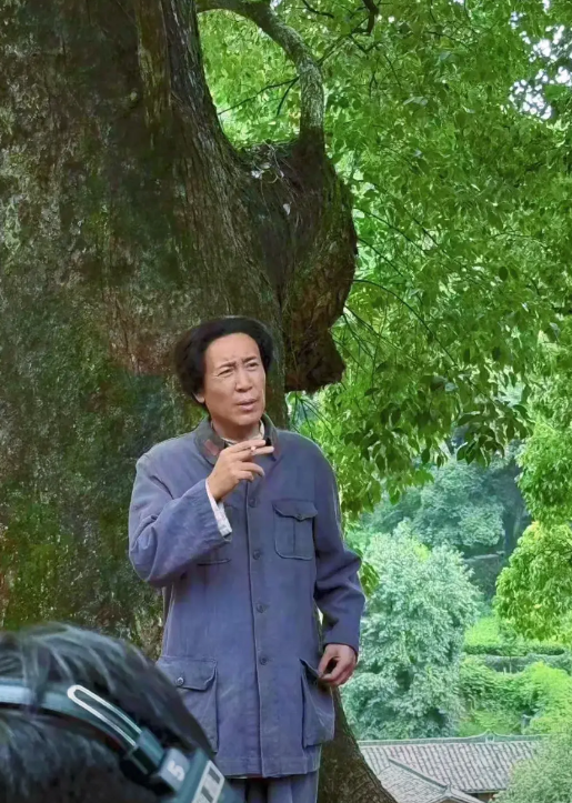 《伟大的长征》剧组，于和伟穿着旧军装，靠在树上皱着眉头，一口一口抽烟，已经有了影