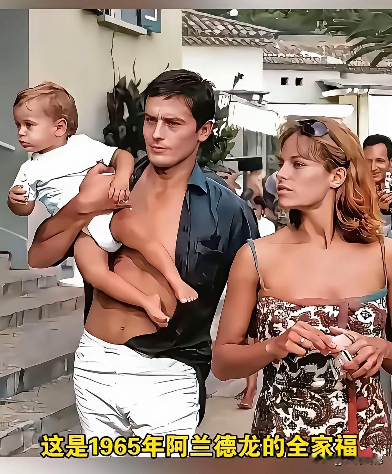 阿兰德龙在1965年的时候，怀里抱着自己的孩子，身边站着自己的妻子，一家三口，其