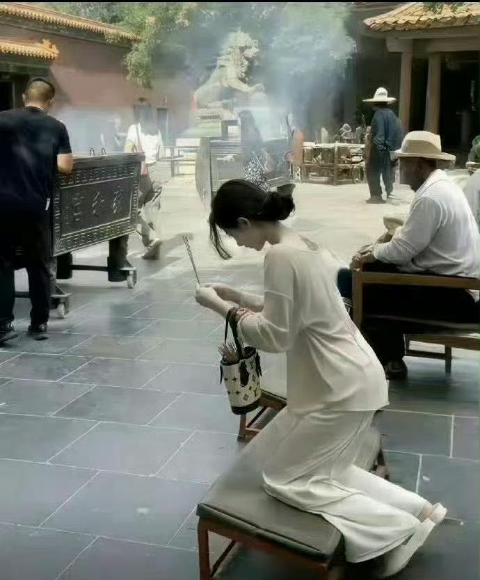 网友分享这样一张照片：一身素雅白衣，手里拎着LV包包，在寺庙虔诚烧香拜佛🙏