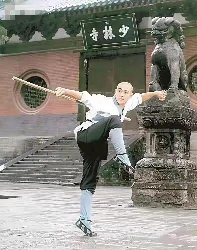 李连杰当年最经典的一张照片。在古寺庭院中，一僧人正专注演练传统武术，棍影翻飞，