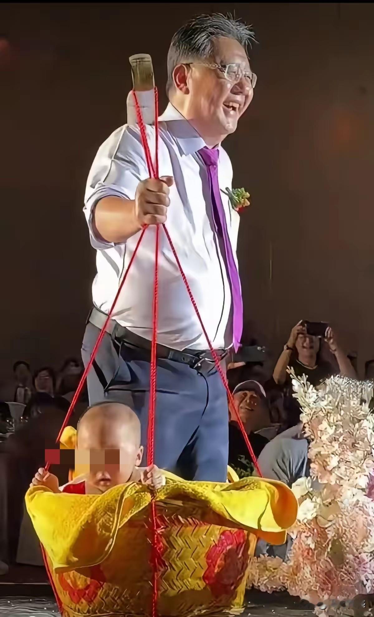 爷爷用扁担挑着龙凤胎孙子孙女，参加了儿子儿媳的婚礼，这场面绝对是别出心裁，别开生
