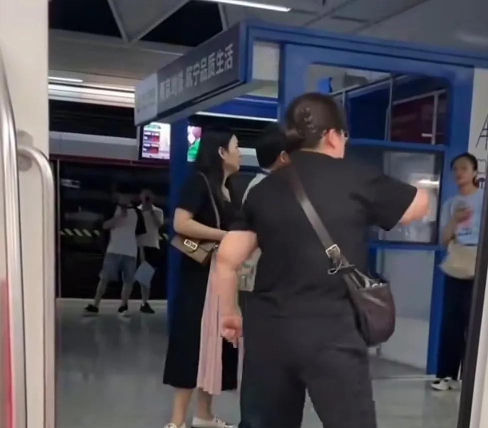 南京地铁上，一穿黑上衣的女子坐过站了，站在地铁站台上与车厢之间，不愿意下车，工作