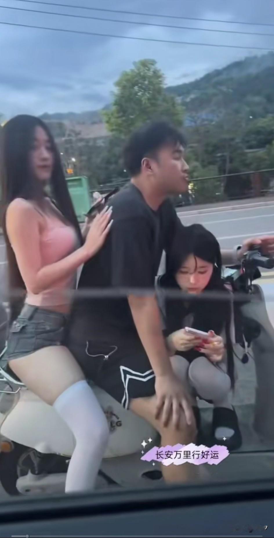 男子和朋友开车等红灯，没想到旁边停了一辆电动车，一哥们后面坐着个美女，前面