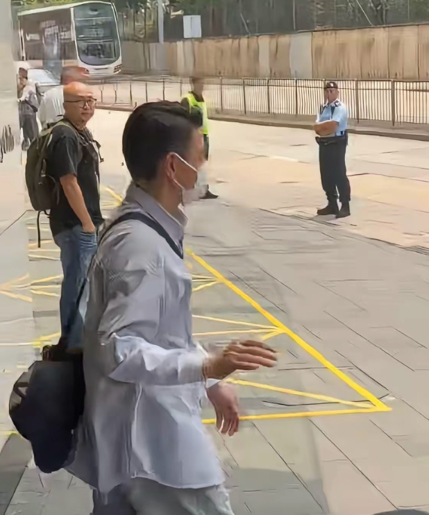 香港大明星刘德华穿着休闲衬衫过肩背着个小包，迈着轻快的步伐走出来，一个跨步就踏