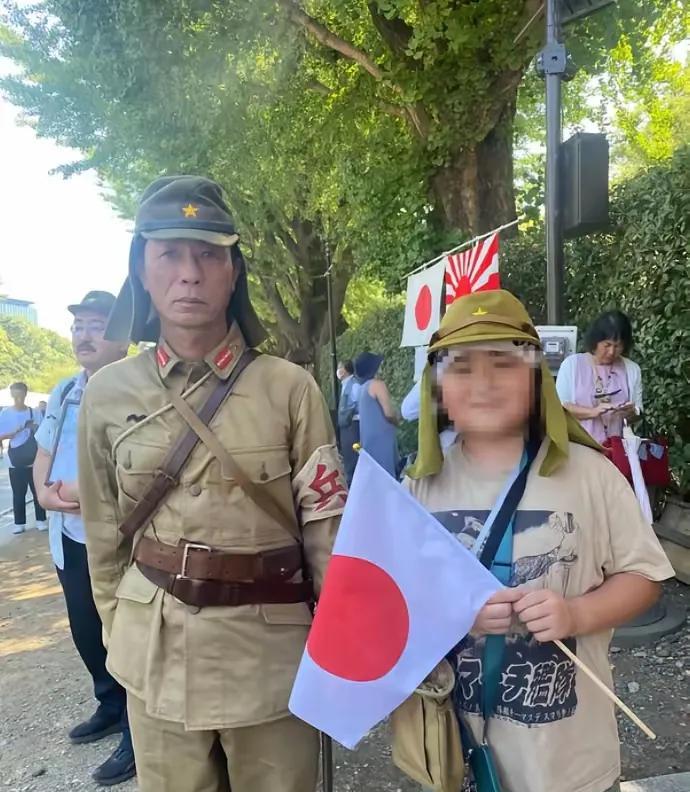 这父子二人，身着二战时期日寇的军装，参拜靖国神社，神气活现的摆拍。这场景，凸显