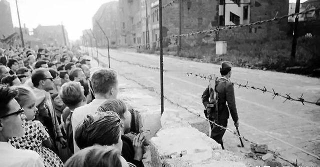 1990年柏林墙即将被拆除前，西德居民热情地伸过手希望和东德军警握手，但军警只是