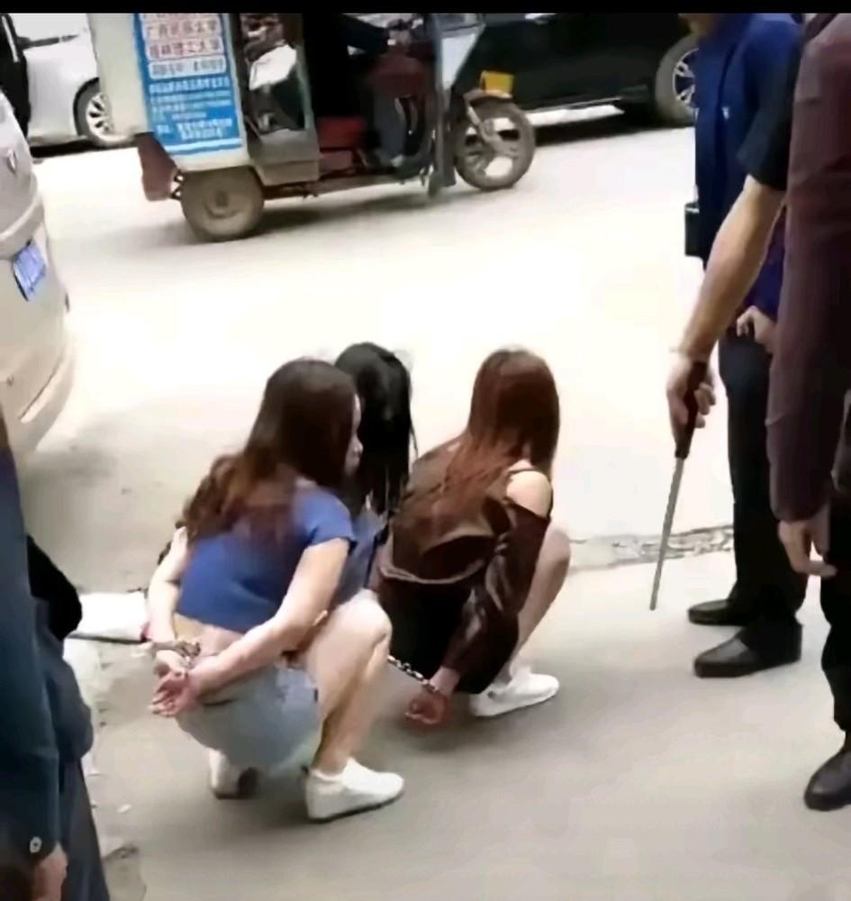真的很同情三位小姐姐，她们究竟做了什么错事，竟然下蹲着还佩戴手铐，旁边是手