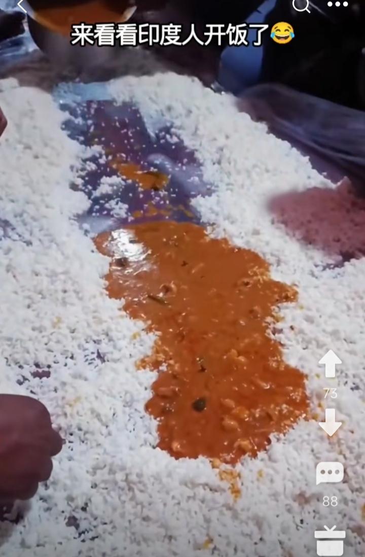 印度人开饭了。一群人席地而坐，把大米饭铺在胶布上，再淋上黄中带黑的咖喱酱，然后