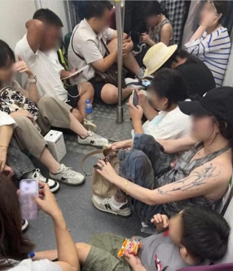有香港市民搭乘港铁的时候，遇上这么一幕，一节车厢的中间过道，十多名旅客直接坐在地