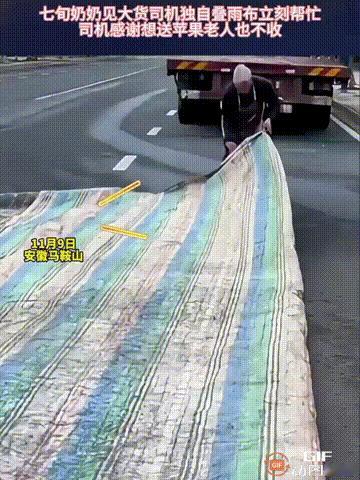 安徽马鞍山一位货车司机在路边叠雨布，由于雨布非常大，他一个人叠起来很不方便，只能