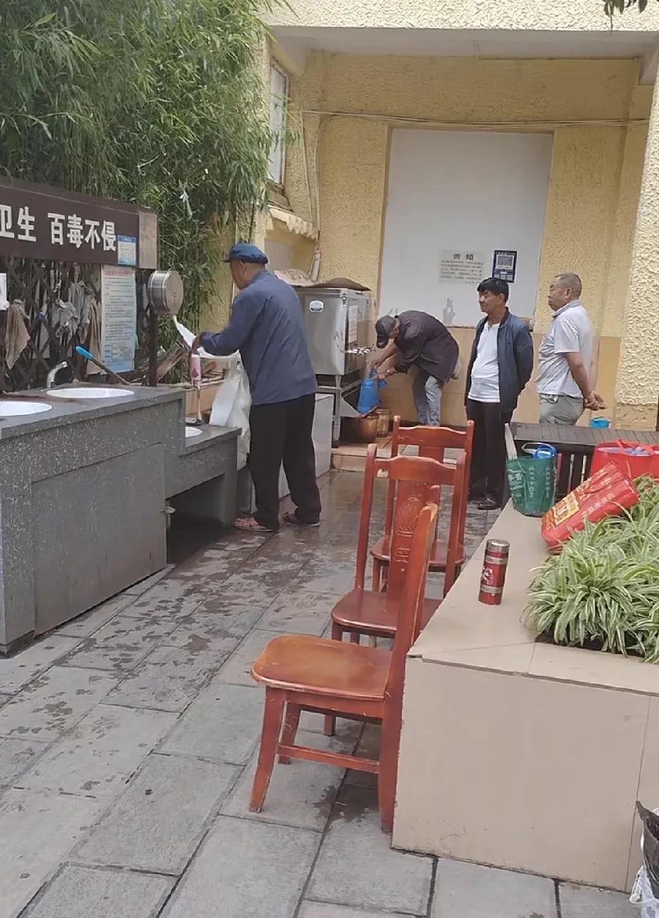 从图片上来看，这应该是一家医院的公共打水点，有几名大爷在此打热水，其中一名穿灰色