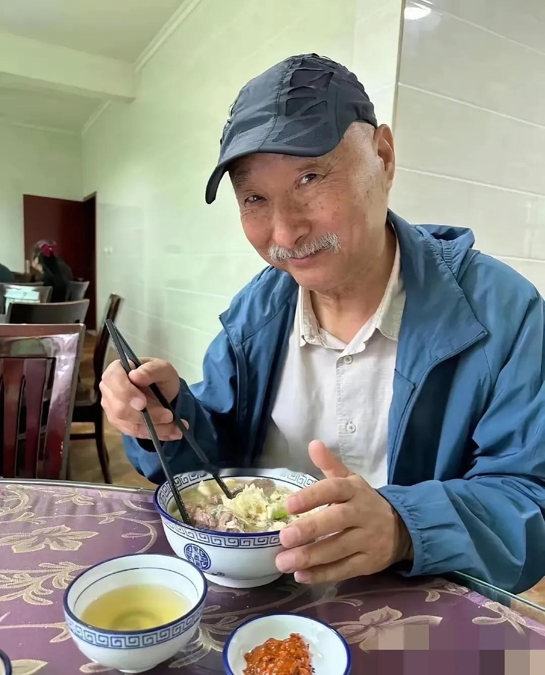 陈佩斯老师面带微笑，正享受着一碗热腾腾的汤面，生活气息浓厚。陈佩斯老师从小品《吃