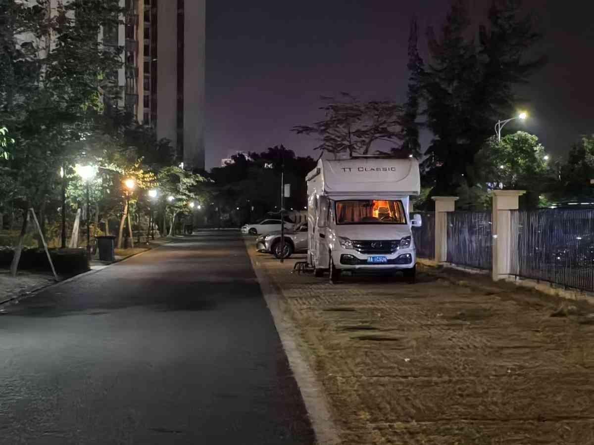 一辆黑龙江来的房车，在小区里停了四天了。业主群里有人拍了张照片。晚上车里亮着灯