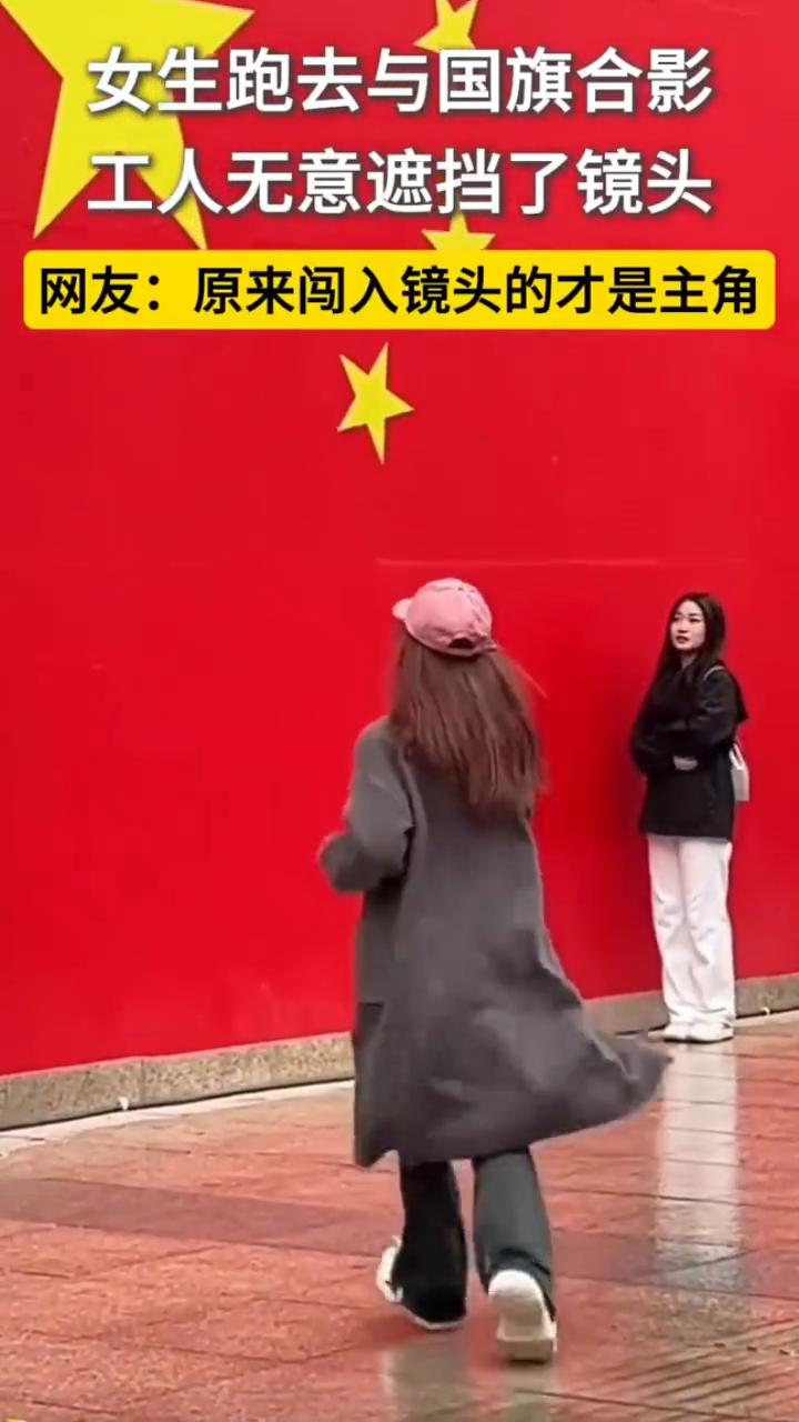 女生跑去与国旗合影，工人无意遮挡了镜头。网友：原来闯入镜头的才是主角。