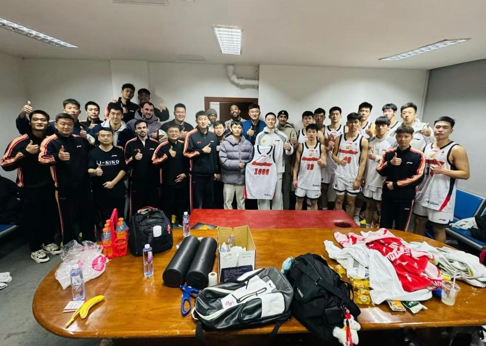 广东队赛后更衣室全员一齐庆祝队史第1000场胜利，胡明轩和徐杰并肩展示纪念球衣，