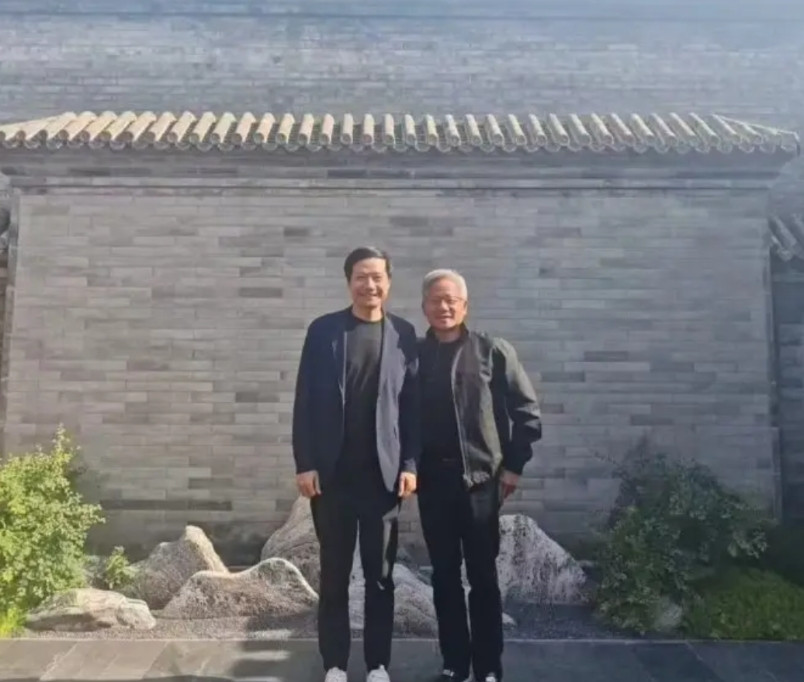 照片存疑。黄仁勋又来了，应该是为了芯片还，和雷布斯合影。俩人合影的背景墙