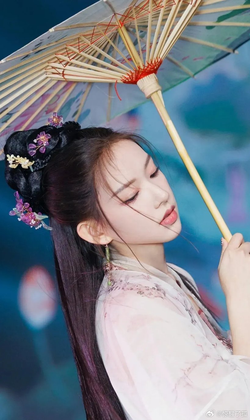 程潇身着浅纹汉服，执花伞垂红流苏，发髻缀饰，尽显温婉古韵。​​​