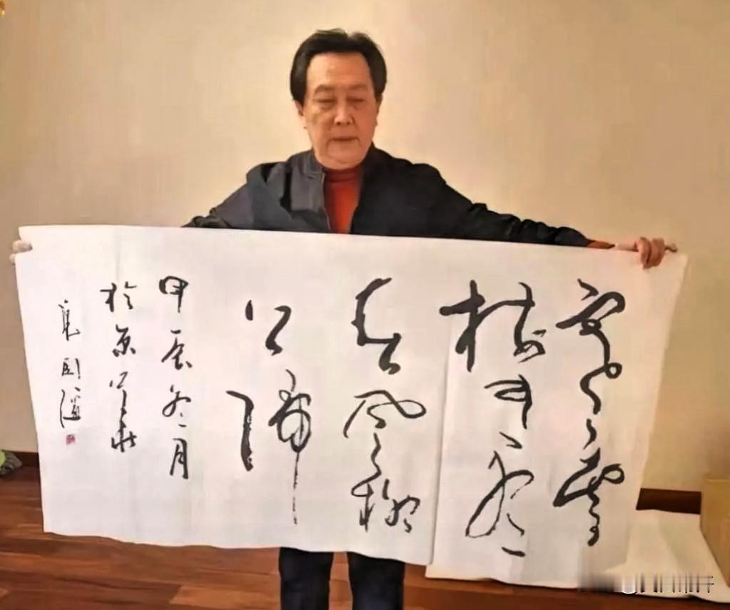 唐国强在家举着自己写的草书拍了张照。他平时除了拍戏，就爱练毛笔字，最拿手的是草书