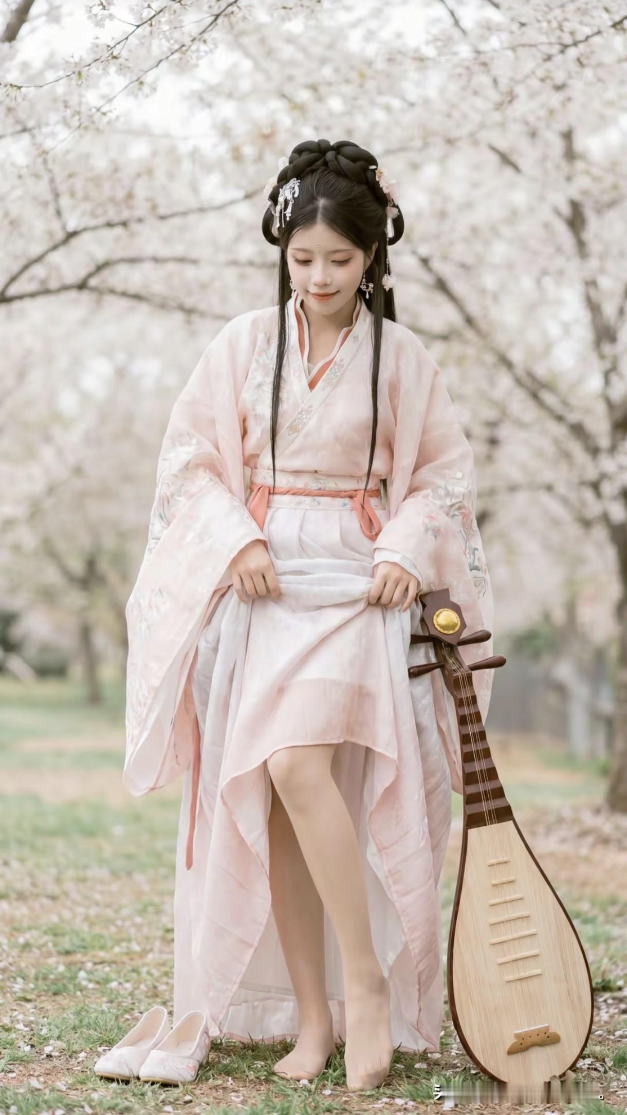 一袭淡粉汉服，怀抱琵琶，像是从唐诗宋词里走出的才女。身畔是漫天飞舞的樱花，