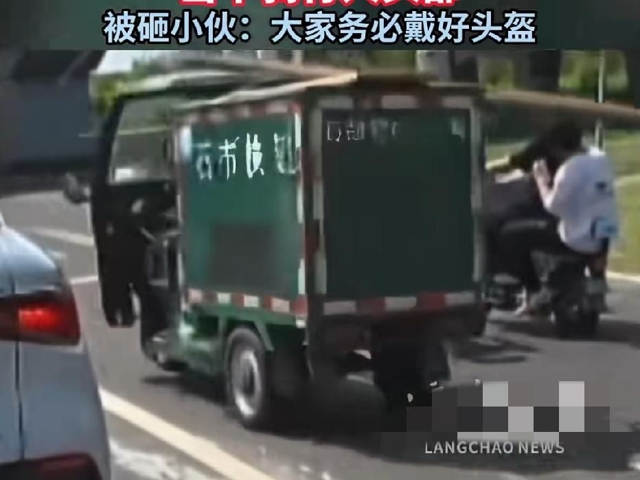 近日河北石家庄，一快递三轮车全速行驶途中，车顶横放的长条包裹打中路边等红灯的小伙